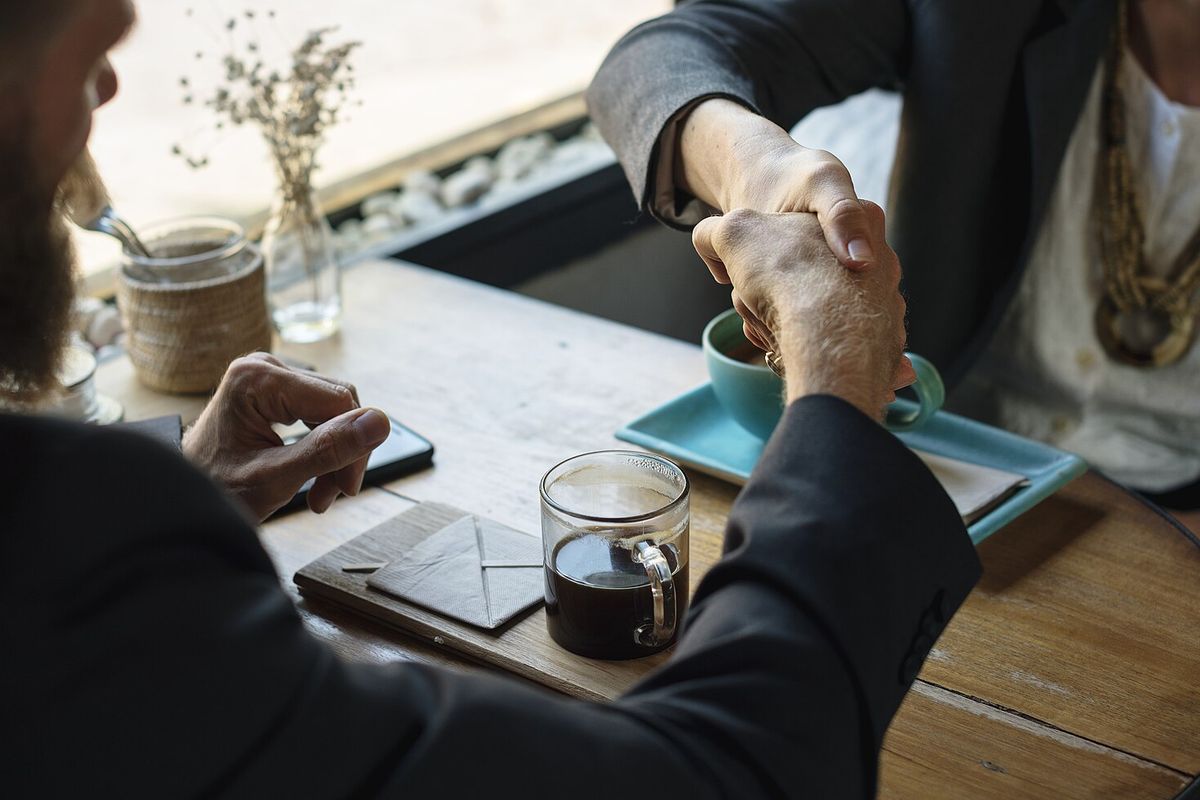 Two people shaking hands across a table